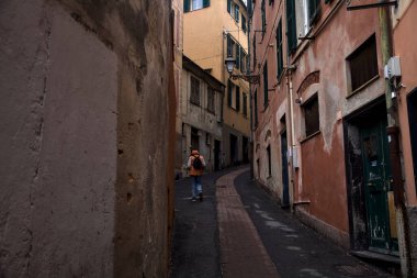 Bulutlu bir günde yüksek binalarla çevrili dar bir dağ yolu.
