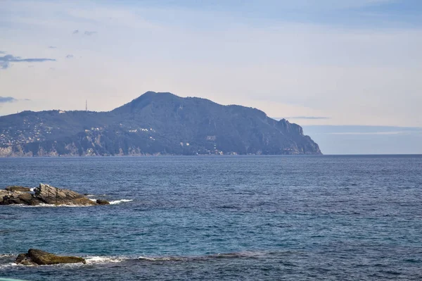 Güneşli bir günde deniz kenarında tarihi evler ve ağaçlarla dolu bir uçurum ve uzaktaki denize kadar uzanan bir kara şeridi.