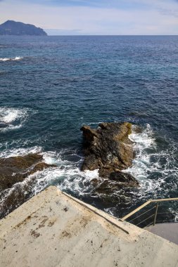 Güneşli bir günde, denizin kenarındaki kayalıkların yanında.