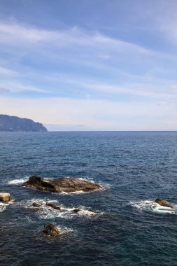 Güneşli bir günde, denizin kenarındaki kayalıkların yanında.