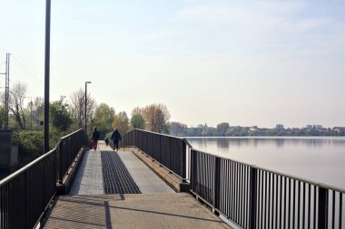 Güneşli bir günde, parktaki bir gölün üzerindeki geçit.
