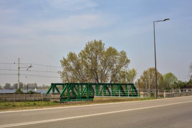 Gölün yanında bir yol ve güneşli bir günde kenarında demiryolu rayları olan bir park.