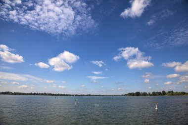 Gökyüzünde bulutlarla güneşli bir günde göl