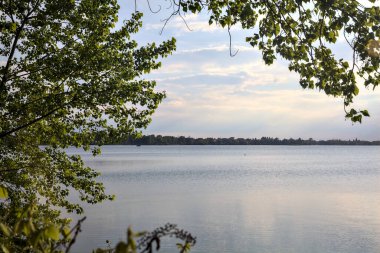 Gün batımında ağaç tepeleriyle çevrili göl.