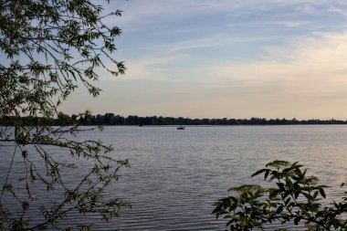 Gün batımında ağaç tepeleriyle çevrili göl.