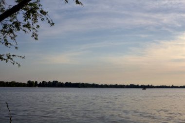 Gün batımında ağaç tepeleriyle çevrili göl.