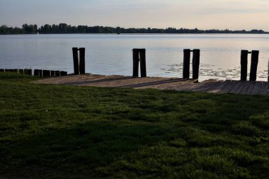 Gün batımında İtalya kırsalındaki göl kıyısında boş bir demirleme yeri.