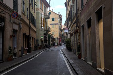 Hafif bir yağış sırasında Cenova Nervi 'de yüksek binaları ve dükkanları olan yokuş yukarı bir yol