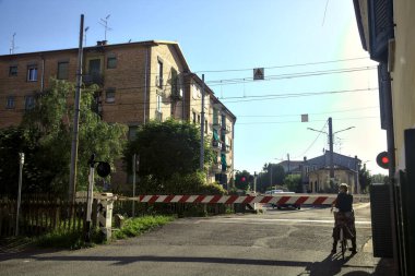 Bisikletçi gün batımında kapalı bir demiryolu geçidinde bekliyor.