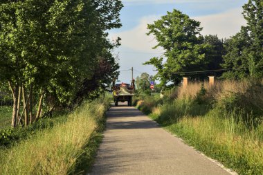 Gün batımında küçük bir köy yolunda traktör.