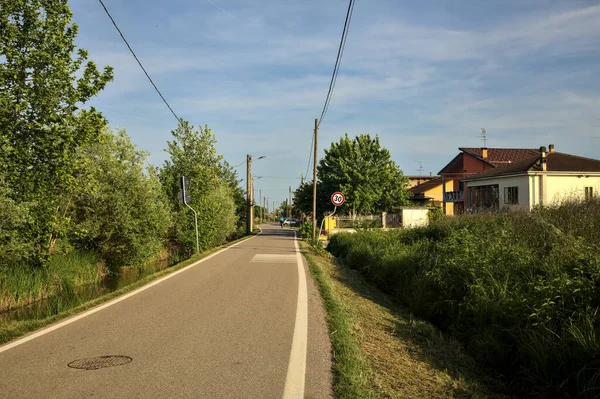 Ağaçlarla çevrili bir köy yolu ve güneşli bir günde bir dere.