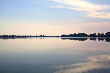 Gün batımında göl karşı kıyıda, uzakta.