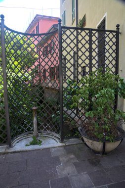 Çitin önündeki eski halk çeşmesi. Bir dizi ev ve bir su akıntısı üzerinde incir çukuru.