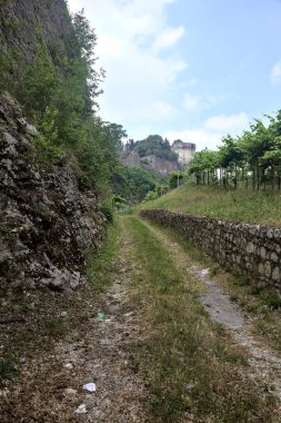 Üzüm bağının ortasındaki toprak yol. Arka planda bir tepenin üzerine güçlendirilmiş toprak.