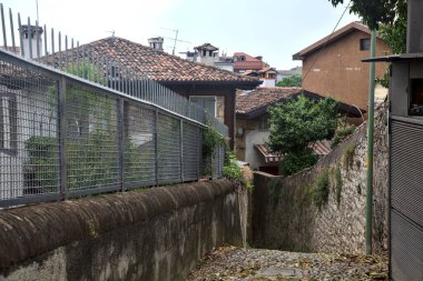 Bulutlu bir günde binalarla çevrili bir dağdan inen patika.