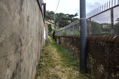 Bir evin kapısına çıkan duvarın yanındaki yokuş yukarı toprak patika.