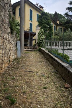 Bir evin kapısına çıkan duvarın yanındaki yokuş yukarı toprak patika.