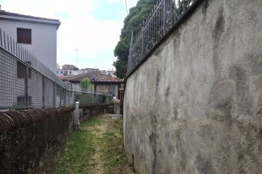 Bulutlu bir günde binalarla çevrili bir dağdan inen patika.