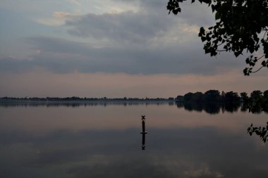 Gün batımında göl, gökyüzü suya gömülmüş.
