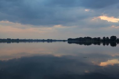 Gün batımında göl, gökyüzü suya gömülmüş.
