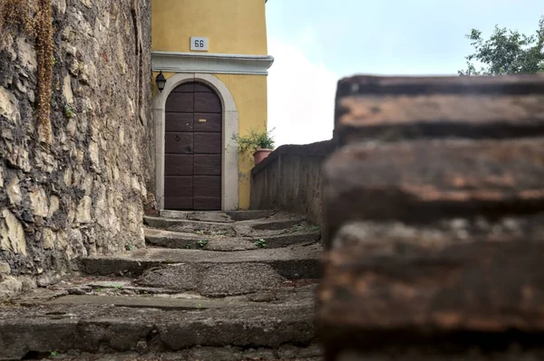 Stone staircase next to a wall that leads to a door of a house