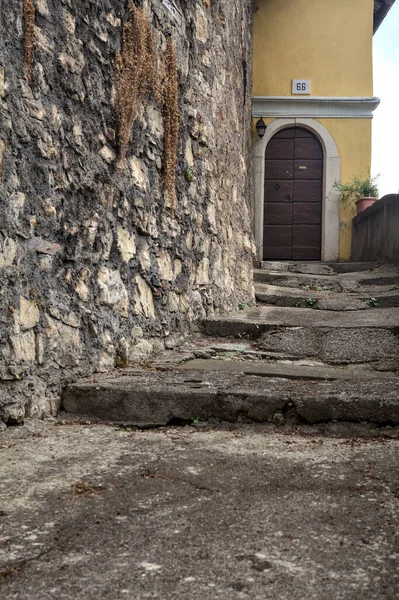 Stone staircase next to a wall that leads to a door of a house