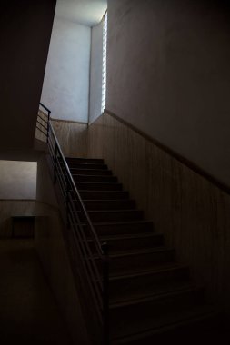 Pencereden gelen zayıf bir ışıkla aydınlatılan merdiven.