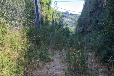 Terk edilmiş patika, uçurumun kenarındaki gölgede.