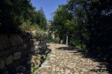Cobbled path by the edge of a cliff with trees on a clear sunny day in a park