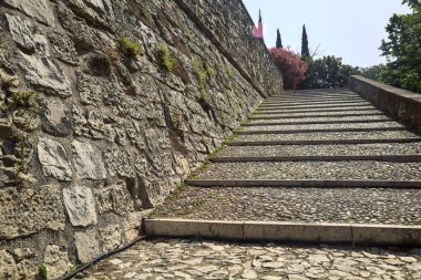 Güneşli bir günde, bir şatoda taş bir duvarın yanında kaldırımlı bir geçit ve adımlar.