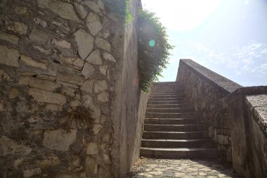 Merdiven, güneş tarafından aydınlatılan taş duvar tezgahının yanında.