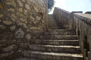 Merdiven, güneş tarafından aydınlatılan taş duvar tezgahının yanında.