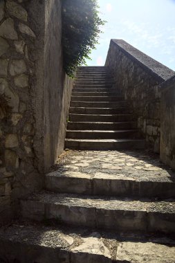 Merdiven, güneş tarafından aydınlatılan taş duvar tezgahının yanında.