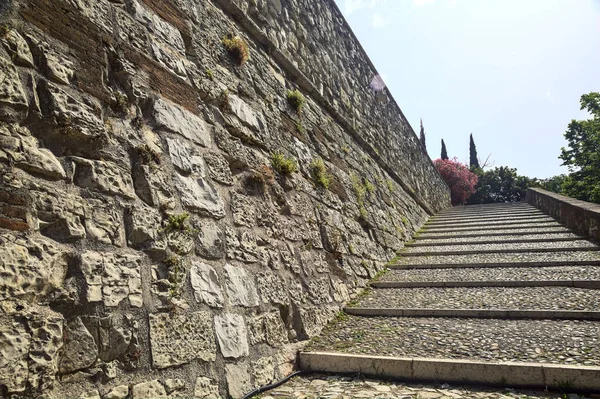 Cobbled passage and steps next to a stone wall in a castle on a sunny day