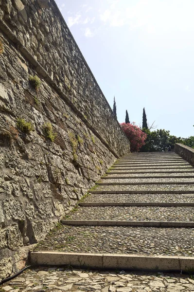Cobbled passage and steps next to a stone wall in a castle on a sunny day