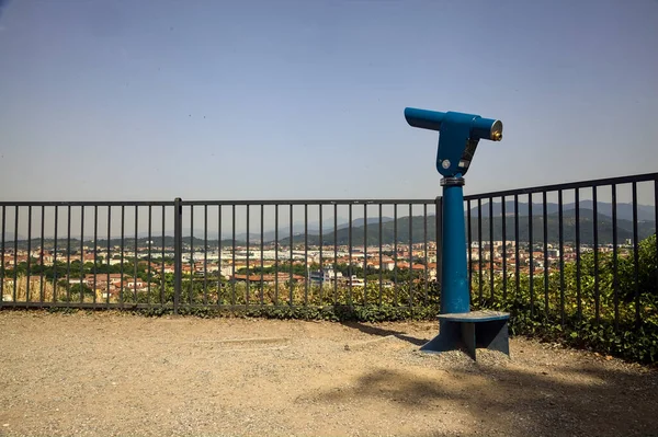 Viewpoint with a coin operated eyeglass on a balcony in a park on a sunny day with a city below