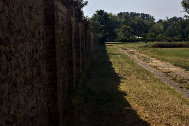 Güneşli bir günde, bir parkta, sınır duvarının yanındaki toprak yol.