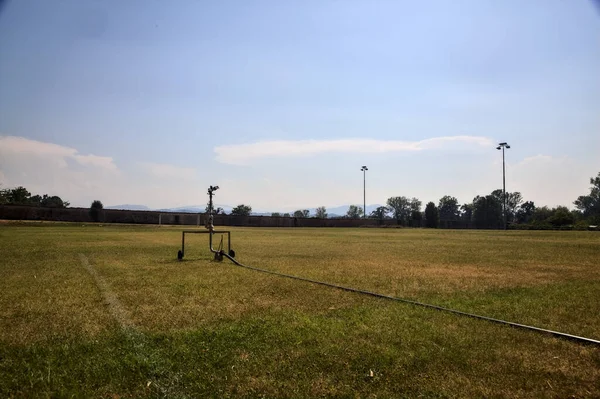 Sprinkler Aan Rand Van Een Versleten Voetbalveld Een Zonnige Dag — Stockfoto