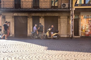 Elder people by the edge of a pavement in a square at daytime