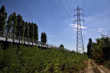 Dirt path with trees next to a highway on a summer day in the italian countryside