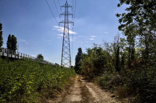 Dirt path with trees next to a highway on a summer day in the italian countryside