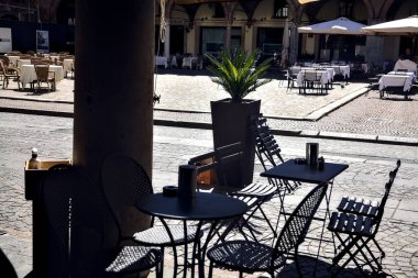 Tables and chairs in the shade under a porchway