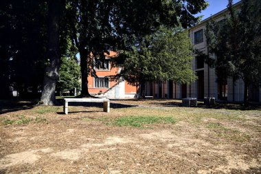 Stone benches in a park next to a building on a sunny day