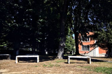 Stone benches in a park next to a building on a sunny day