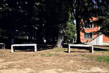 Stone benches in a park next to a building on a sunny day