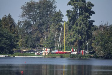 Göl kıyısındaki bir ormanda, uzaklardan görülen bir iskelede.