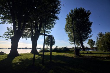 Gün batımında göl ağaçlarla çevrili ve kıyıdan görülüyor.