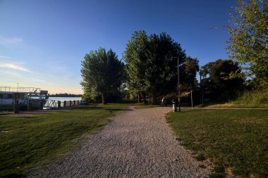 Gün batımında göl kıyısındaki bir parkta toprak yol.