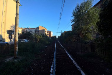 Gün batımında yanında ağaçlar ve binalar olan demiryolu geçidi