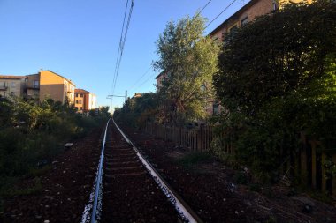 Gün batımında yanında ağaçlar ve binalar olan demiryolu geçidi